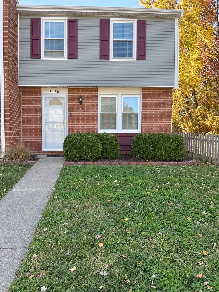 The same house on beyonvital.com: the same siding, burgundy shutters, brick, storm door, house number, shrubs and picket fence, shot square on with the verticals straight.