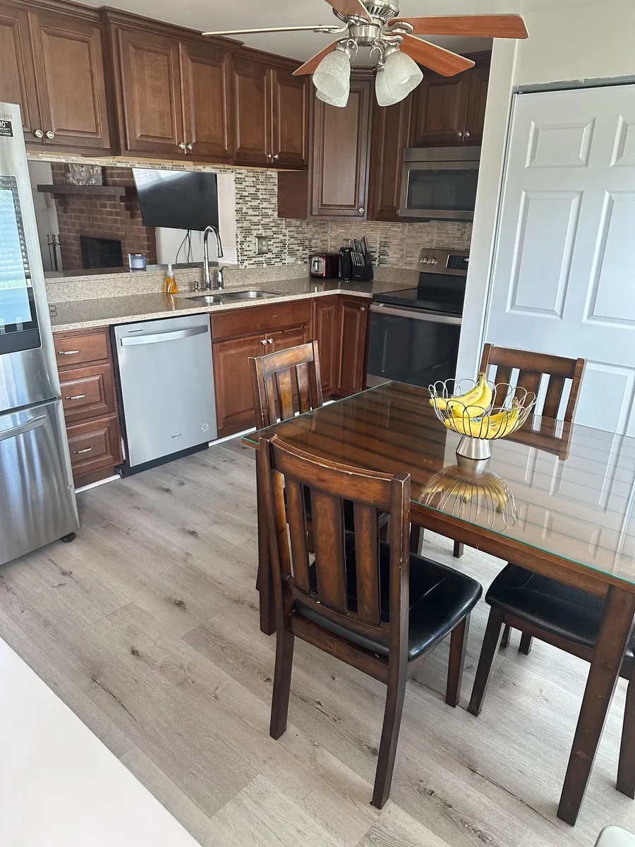 The kitchen and dining table as the owner photographed it on a phone, tilted, with the fridge cut off at the edge.