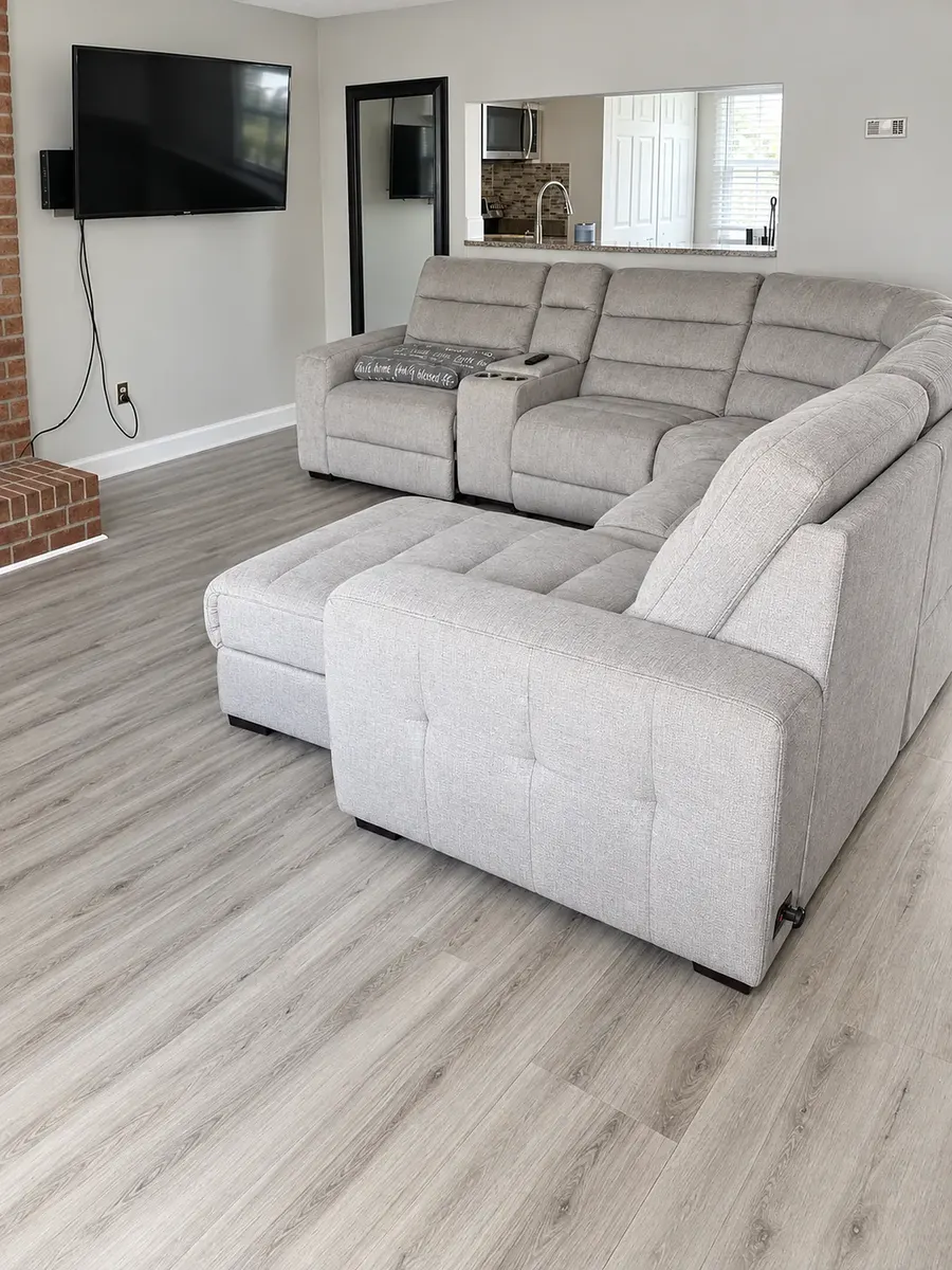 The same living room on beyonvital.com: the same sectional, TV, brick column and kitchen pass-through, now level, evenly lit and colour-corrected.